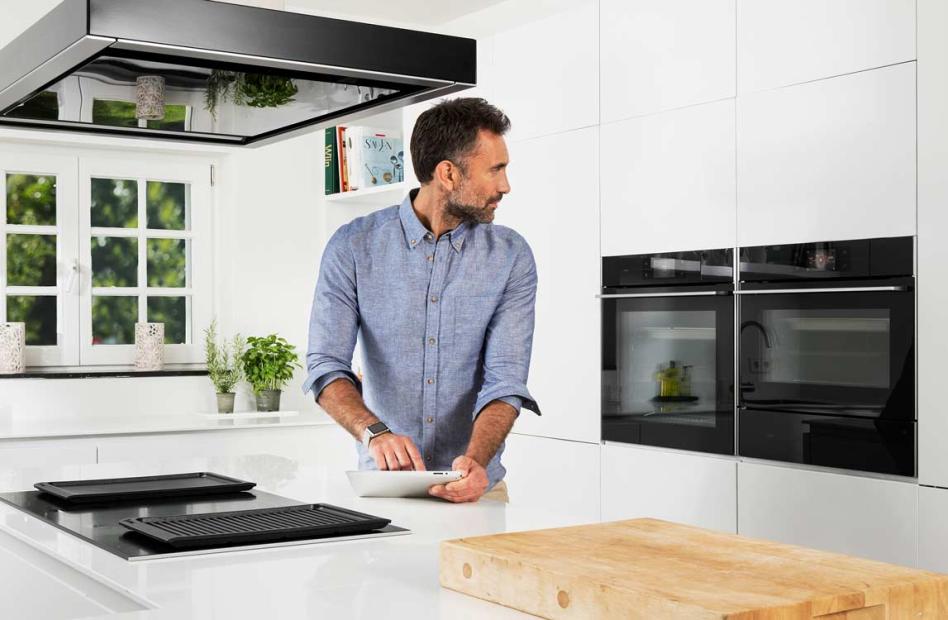 Man holding an iPad sending instructions to the oven